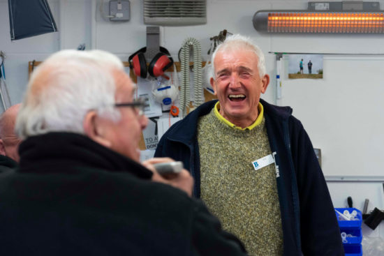 Two older male volunteers laughing