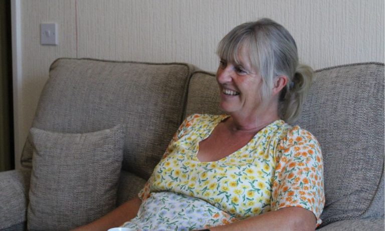 Image of a smiling woman sitting on a sofa