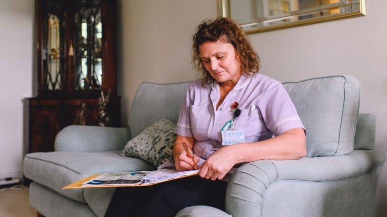 A nurse in a patient's home writing a document