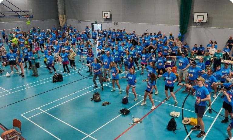 A big group of people doing a warm up in a school gym