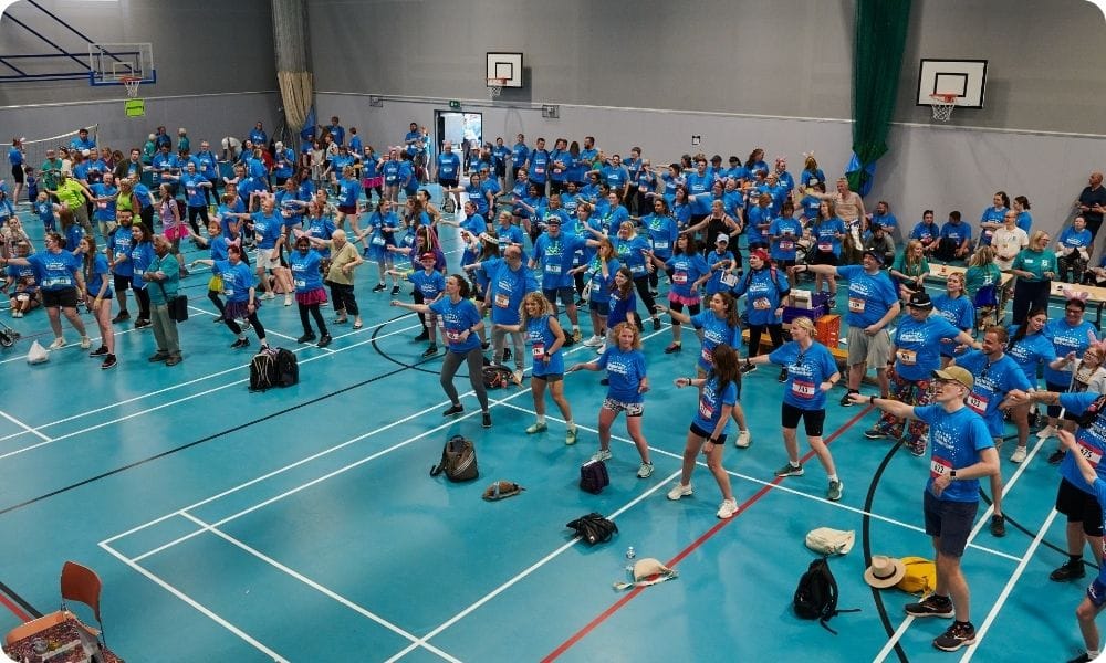 A big group of people doing a warm up in a school gym
