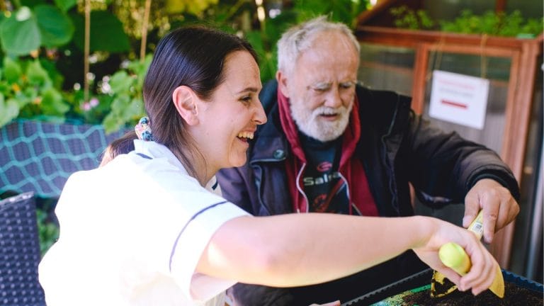 Female physiotherapist wearing a white uniform doing gardening with a male patient