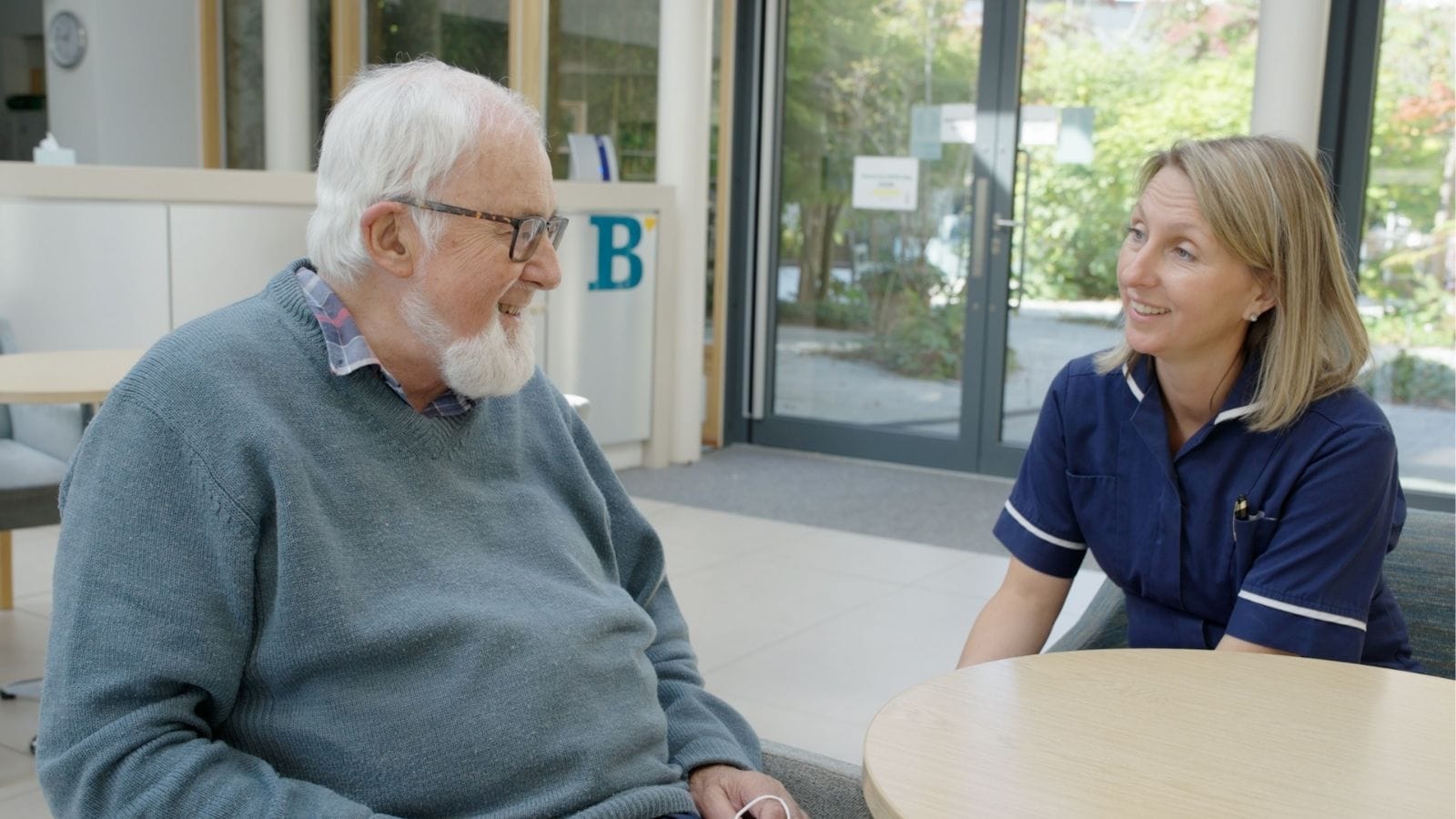A patient sits at a table with a member of the nursing team at St Barnabas House