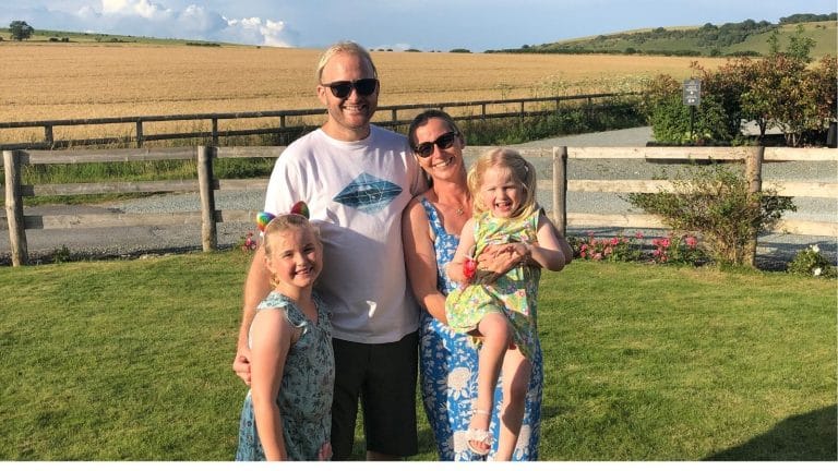Joe, Tania and their daughters Eryn and Felicity stand in a beautiful summer lansdcape, smiling