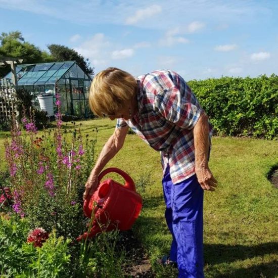 Liz is pictured watering her garden on a summer's day