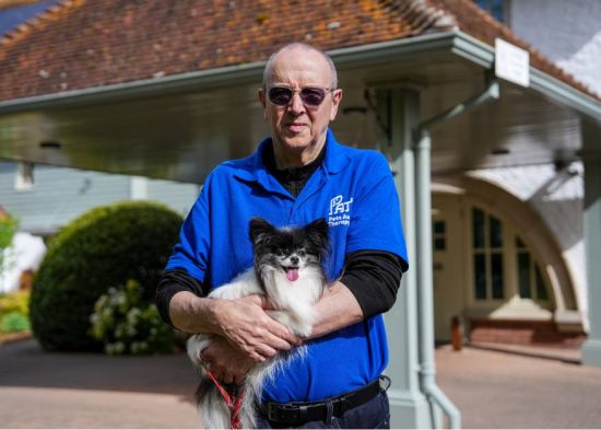 a volunteer holding his pets as therapy dog tuppence in his arms