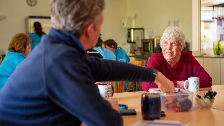 A volunteer sitting in the canteen at St barnabas house with a member of the gardening team