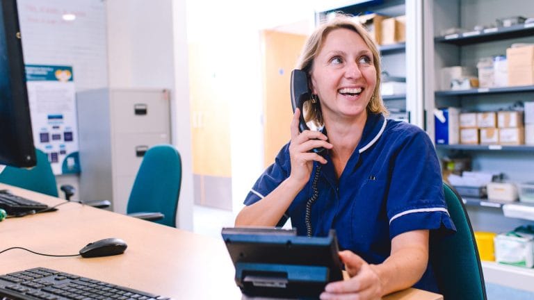 A nurse holds a phone while smiling off-camera