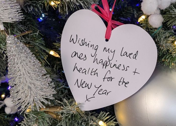 a christmas tree with white heart decoration showing handwritten message 