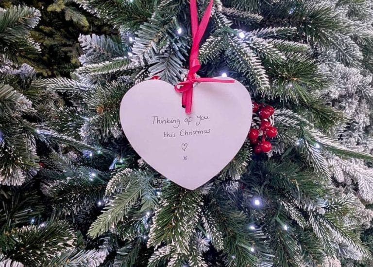 a christmas tree with white heart decoration showing handwritten message 