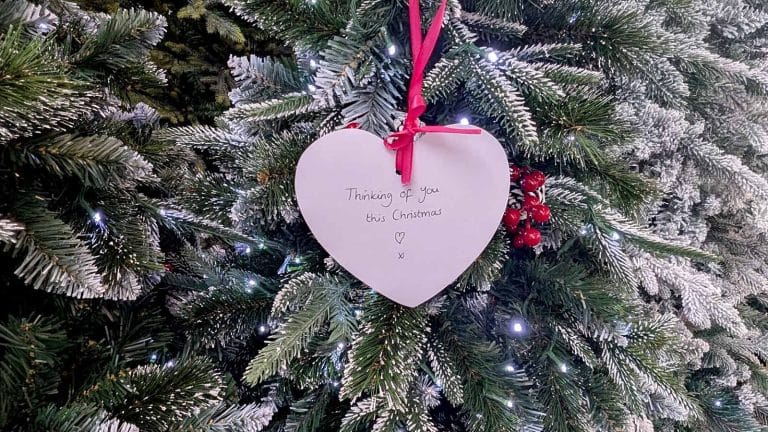 a christmas tree with white heart decoration showing handwritten message 
